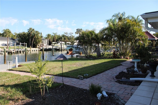 view of property's community featuring a water view, fence, a dock, and a yard