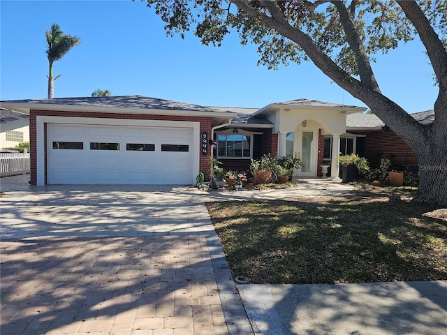 ranch-style home featuring a garage, decorative driveway, and brick siding