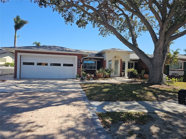 ranch-style home featuring a garage, decorative driveway, and brick siding