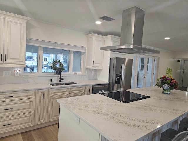 kitchen with island range hood, light stone countertops, black appliances, a kitchen bar, and a sink