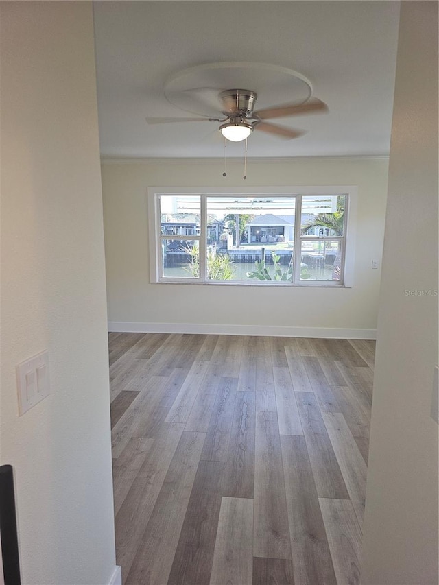 empty room featuring light wood-type flooring, plenty of natural light, baseboards, and ceiling fan