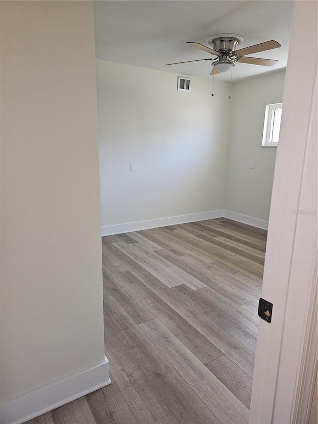 empty room with a ceiling fan, baseboards, visible vents, and light wood finished floors