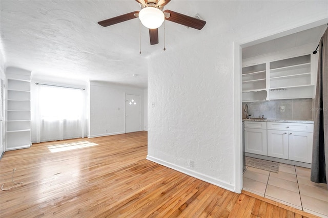 unfurnished room with sink, light hardwood / wood-style flooring, a textured ceiling, and ceiling fan