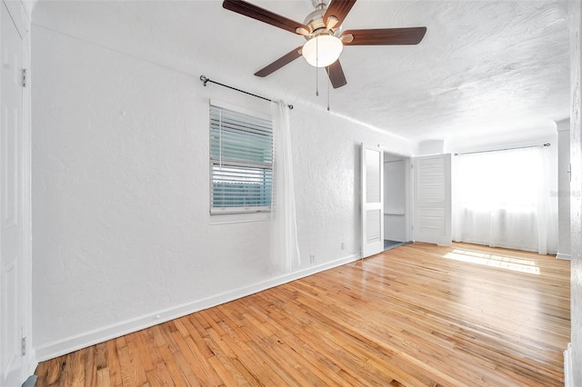 unfurnished bedroom featuring multiple windows, ceiling fan, a textured ceiling, and light hardwood / wood-style flooring