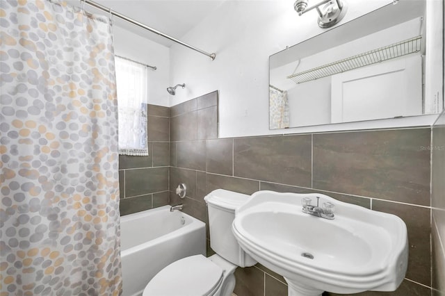 full bathroom featuring sink, tile walls, shower / bath combo with shower curtain, and toilet