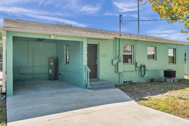 ranch-style house with water heater, a carport, and central AC unit