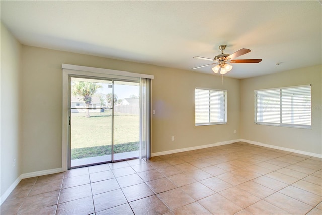 spare room featuring ceiling fan, light tile patterned floors, plenty of natural light, and baseboards