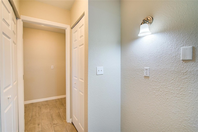 hallway featuring baseboards and light wood-style floors