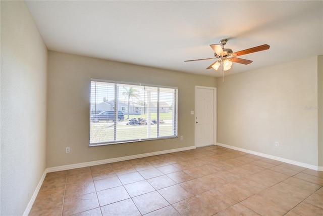 spare room with light tile patterned floors, a ceiling fan, and baseboards