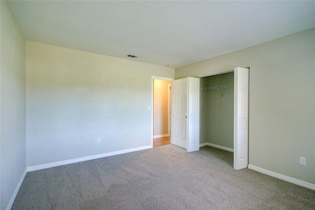 unfurnished bedroom with carpet floors, a closet, visible vents, and baseboards