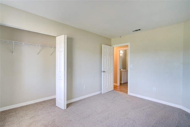 unfurnished bedroom featuring a closet, carpet flooring, visible vents, and baseboards