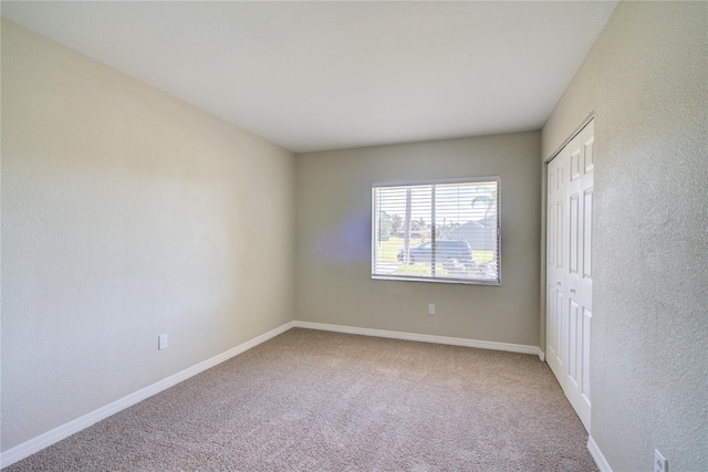 carpeted spare room featuring baseboards