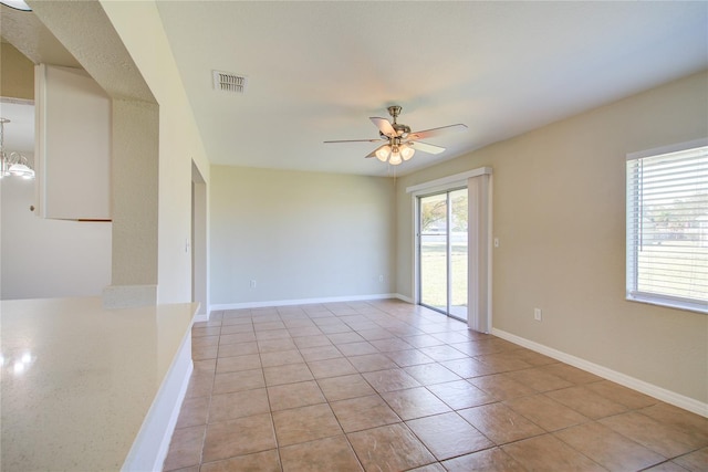 spare room with ceiling fan with notable chandelier, light tile patterned floors, visible vents, and baseboards