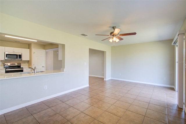 unfurnished room featuring visible vents, a ceiling fan, light tile patterned flooring, a sink, and baseboards