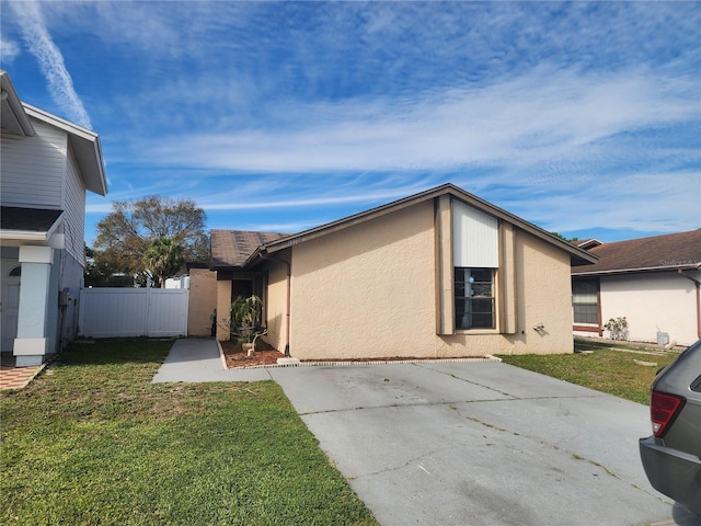 view of property exterior with stucco siding, fence, and a yard