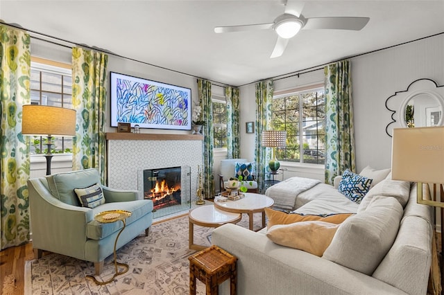 living room with ceiling fan, wood-type flooring, and a tile fireplace