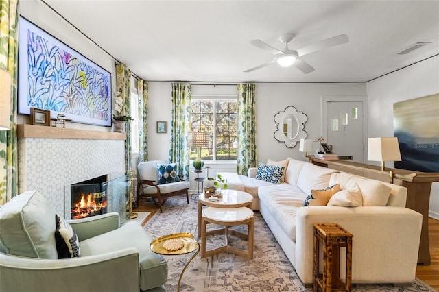 living room featuring ceiling fan, hardwood / wood-style floors, and a fireplace