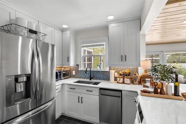 kitchen with appliances with stainless steel finishes, sink, a wealth of natural light, and white cabinets