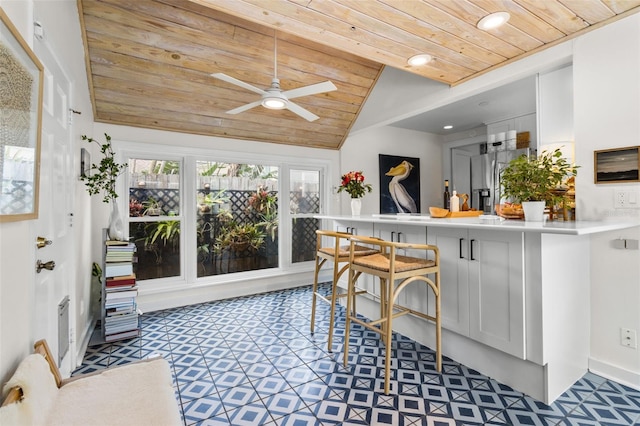 kitchen with wood ceiling, a kitchen bar, stainless steel refrigerator with ice dispenser, and white cabinets