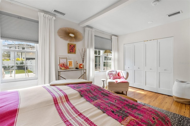 bedroom with hardwood / wood-style flooring, beam ceiling, and a closet