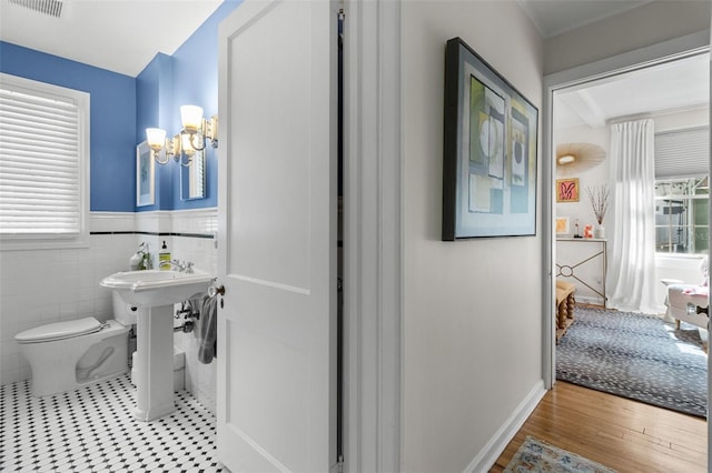 bathroom with tile walls, hardwood / wood-style floors, toilet, and an inviting chandelier