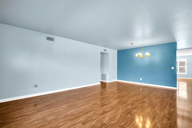 spare room featuring hardwood / wood-style flooring and a chandelier