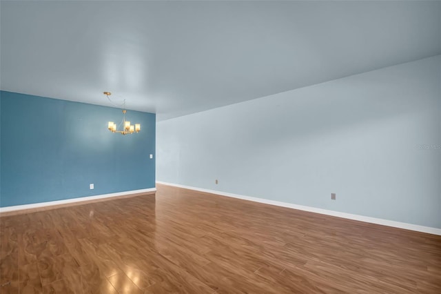 unfurnished room featuring wood-type flooring and a notable chandelier