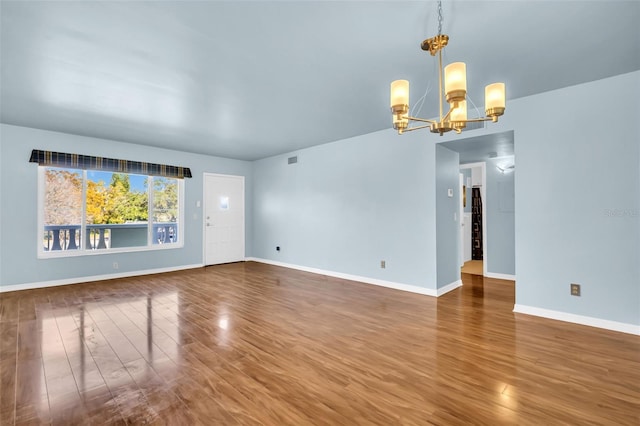 spare room featuring wood-type flooring and a chandelier