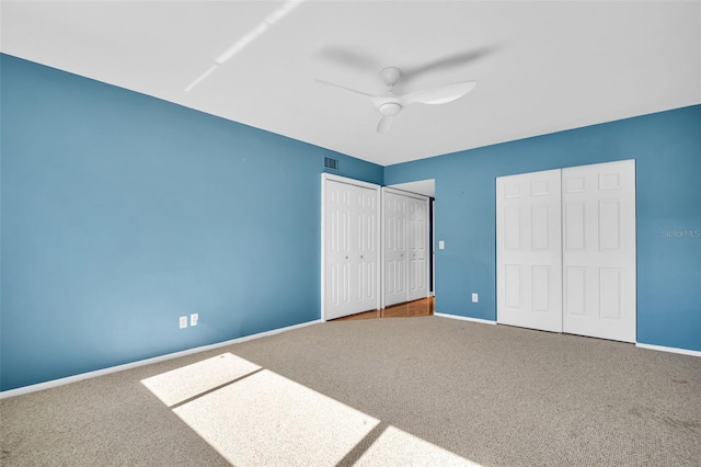 unfurnished bedroom with multiple closets, carpet floors, and ceiling fan