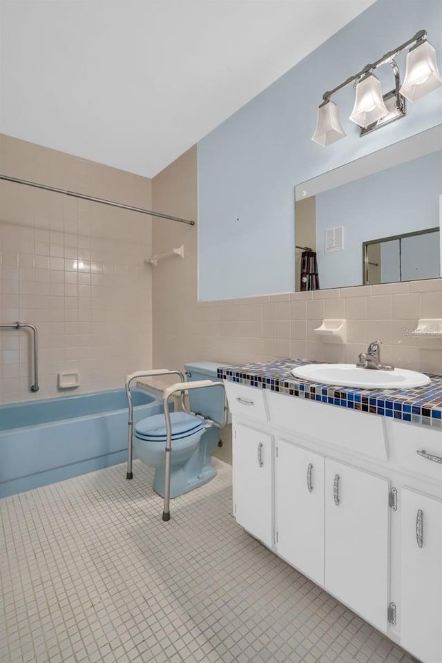 full bathroom with toilet, tasteful backsplash, tiled shower / bath, tile walls, and vanity