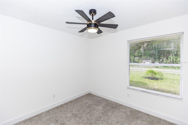 spare room featuring ceiling fan, light colored carpet, and a textured ceiling