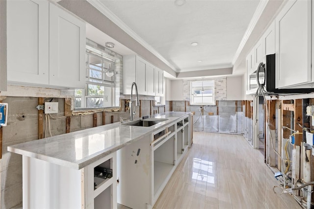 kitchen featuring light stone counters, a healthy amount of sunlight, sink, and white cabinets