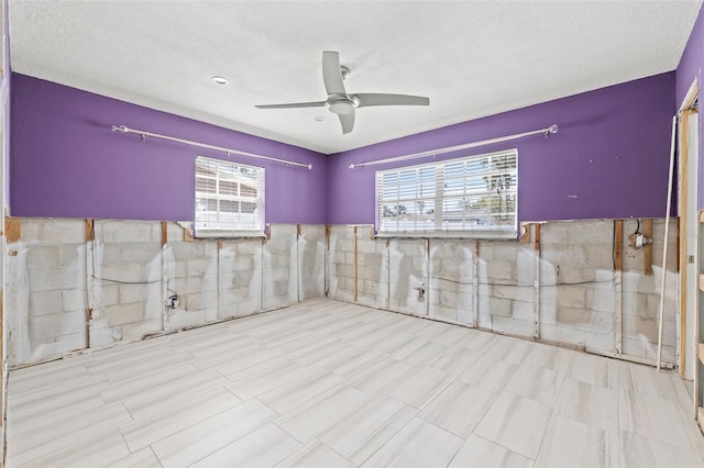 empty room with tile walls, a textured ceiling, and ceiling fan