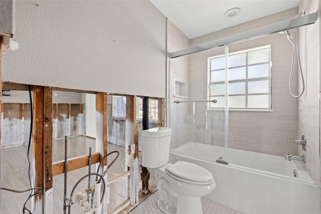 bathroom featuring toilet, plenty of natural light, bath / shower combo with glass door, and tile patterned flooring