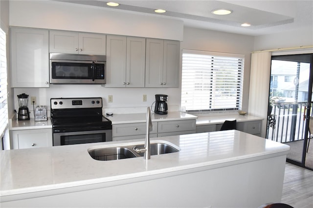 kitchen featuring gray cabinetry, recessed lighting, a sink, light wood-style floors, and appliances with stainless steel finishes