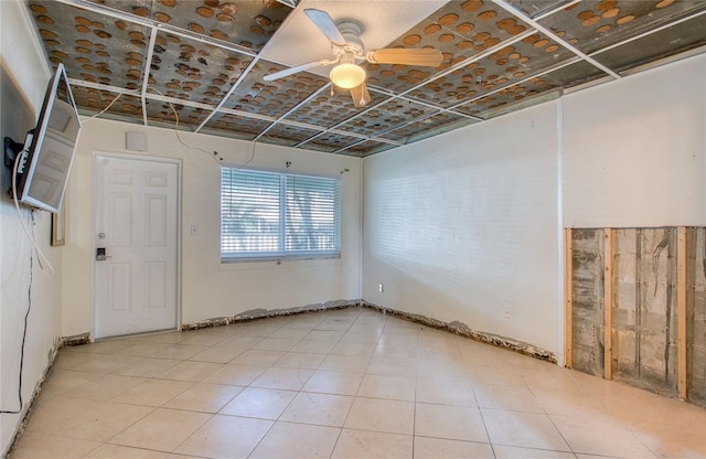 tiled spare room featuring ceiling fan