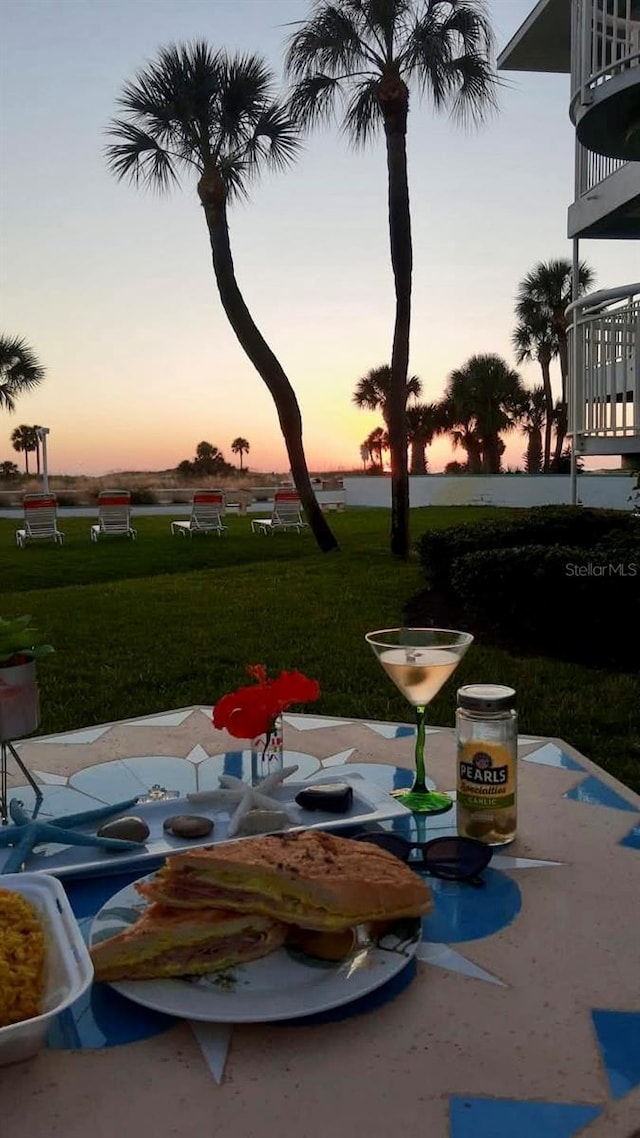 patio terrace at dusk featuring a lawn