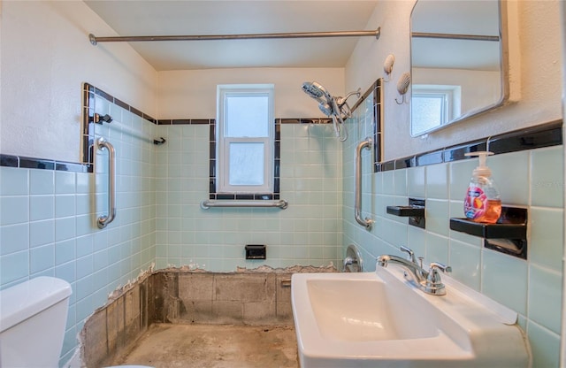 bathroom with tiled shower, sink, tile walls, and toilet