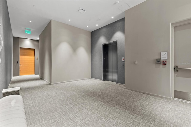 empty room with light colored carpet and elevator