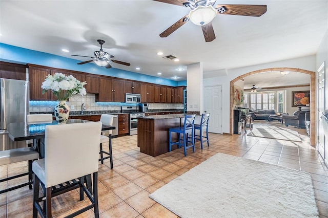 2786 Countryside Blvd Unit 2, Clearwater, FL 33761 - kitchen with backsplash, a kitchen island, stainless steel appliances, dark brown cabinetry, and a kitchen bar