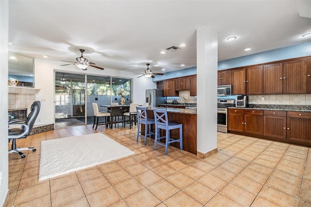 2786 Countryside Blvd Unit 2, Clearwater, FL 33761 - kitchen featuring a tile fireplace, appliances with stainless steel finishes, a kitchen breakfast bar, tasteful backsplash, and light tile patterned flooring