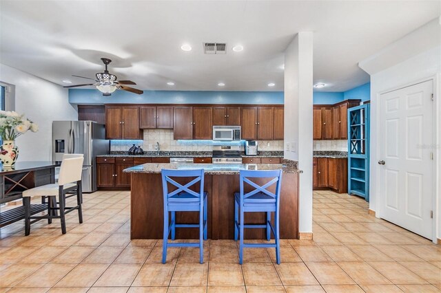2786 Countryside Blvd Unit 2, Clearwater, FL 33761 - kitchen with a center island, dark stone counters, a kitchen breakfast bar, ceiling fan, and stainless steel appliances