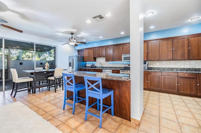 2786 Countryside Blvd Unit 2, Clearwater, FL 33761 - kitchen with ceiling fan, dark stone countertops, a kitchen bar, stainless steel appliances, and a kitchen island