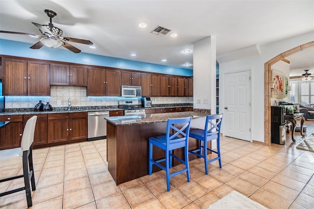 2786 Countryside Blvd Unit 2, Clearwater, FL 33761 - kitchen with a kitchen island, appliances with stainless steel finishes, a breakfast bar area, and dark stone countertops