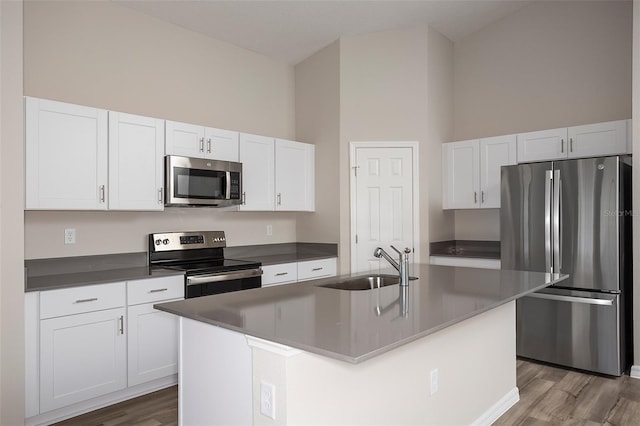 kitchen with sink, stainless steel appliances, a high ceiling, white cabinets, and a center island with sink