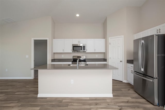 kitchen with appliances with stainless steel finishes, a center island with sink, and white cabinets