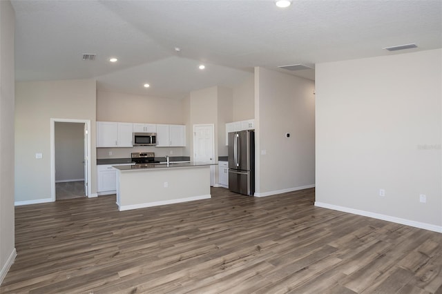 kitchen with sink, dark wood-type flooring, white cabinetry, stainless steel appliances, and an island with sink