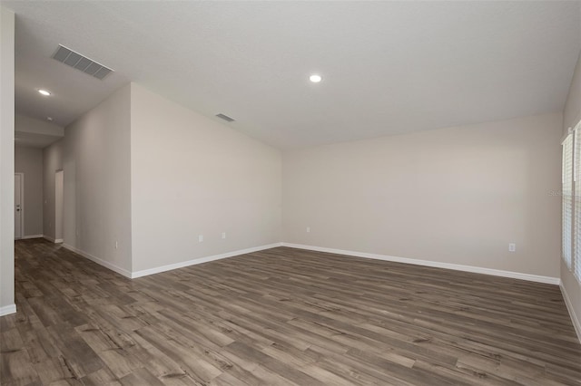 unfurnished room featuring lofted ceiling and dark hardwood / wood-style flooring