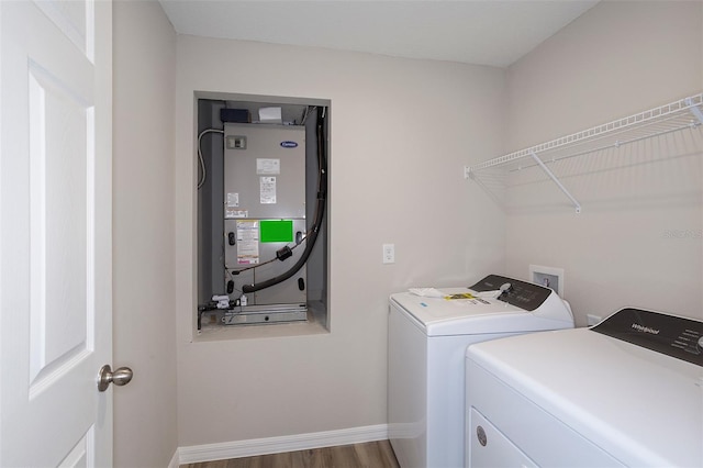 clothes washing area featuring hardwood / wood-style floors, washing machine and dryer, and heating unit