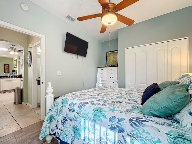 bedroom with a ceiling fan, visible vents, a sink, a closet, and ensuite bathroom